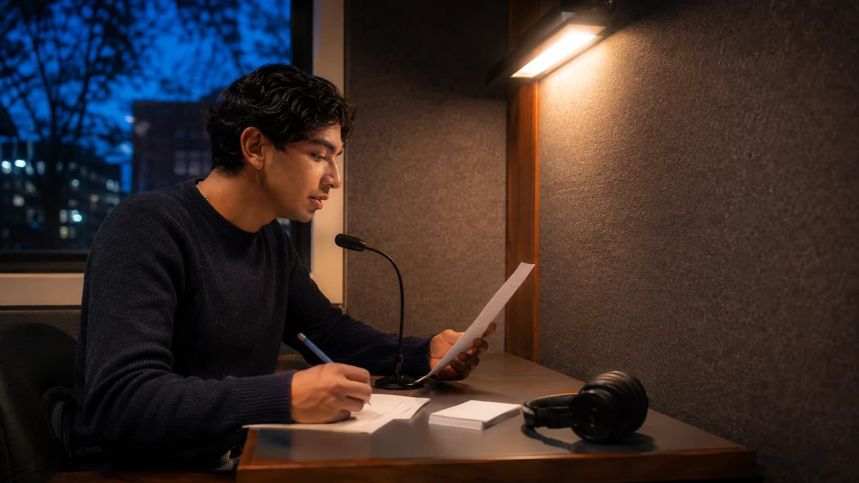 University student reading his English draft aloud in a language practice booth