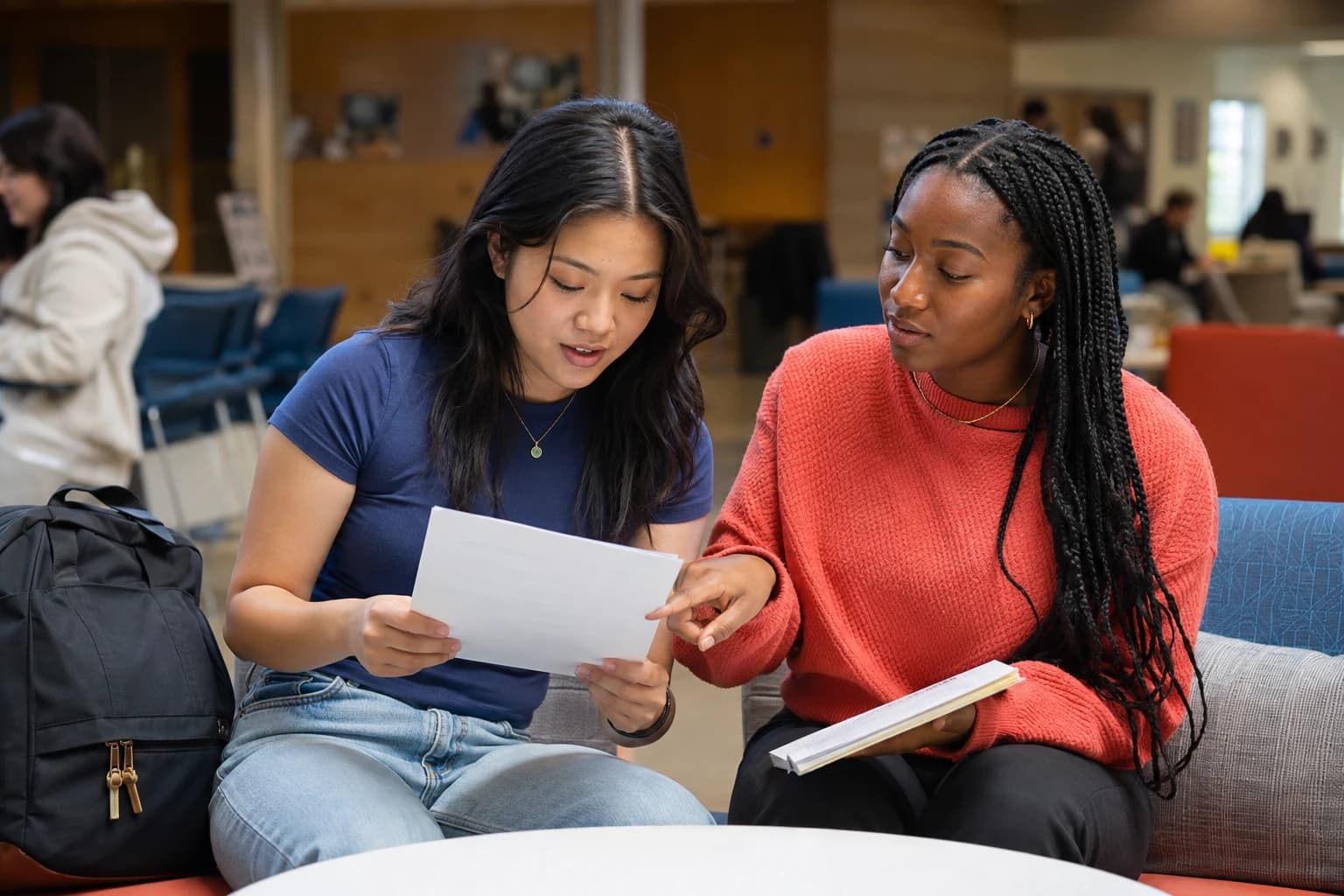 Two university students doing a read aloud review of an English draft in a campus lounge