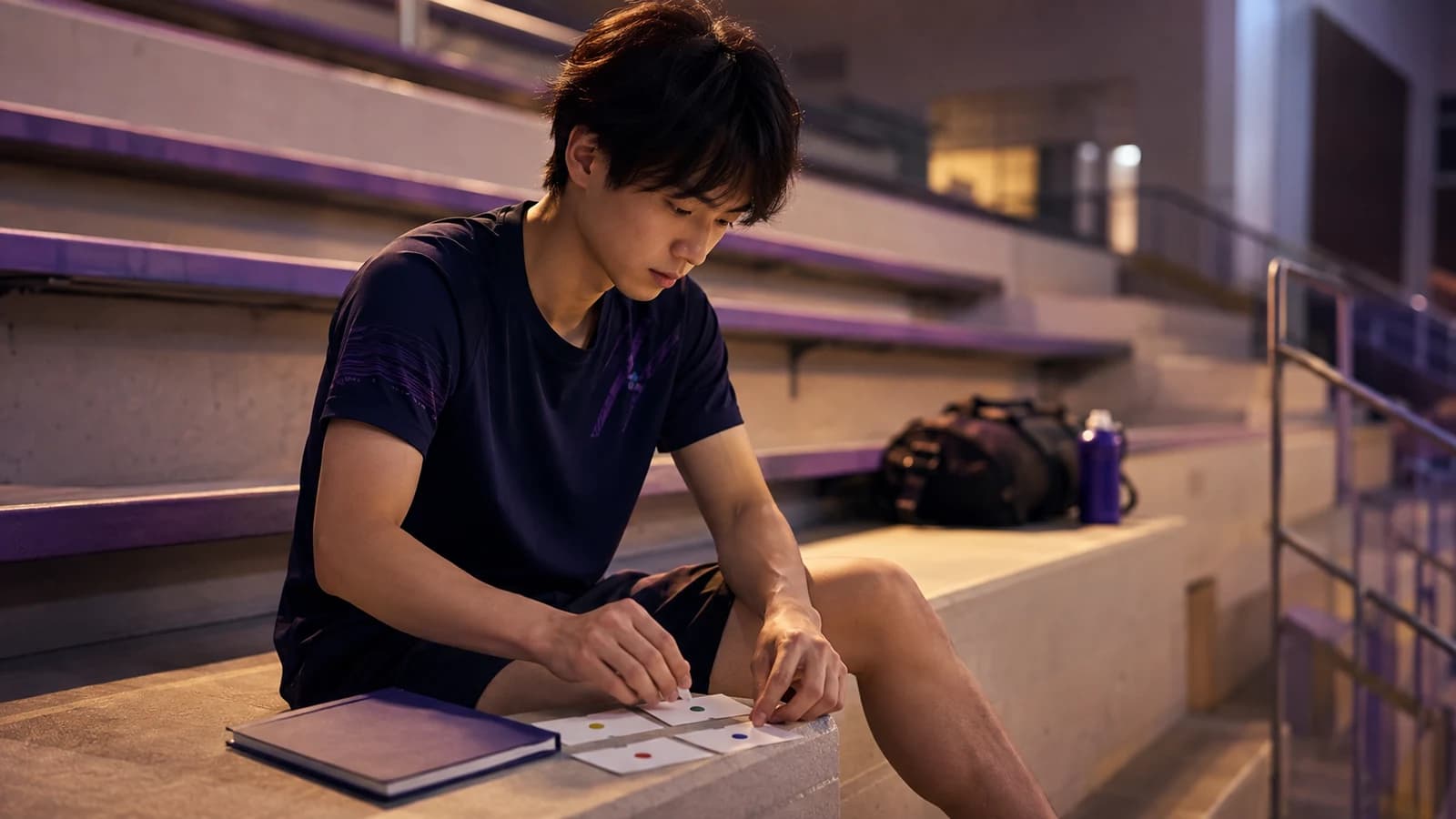 Japanese university student arranging blank statistics practice cards on arena bleachers